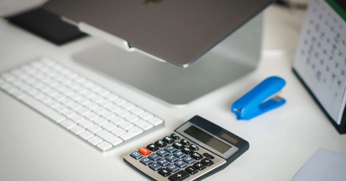 Un bureau de bureau ordonné avec un ordinateur portable, une calculatrice, un clavier et un calendrier pour la planification des affaires.