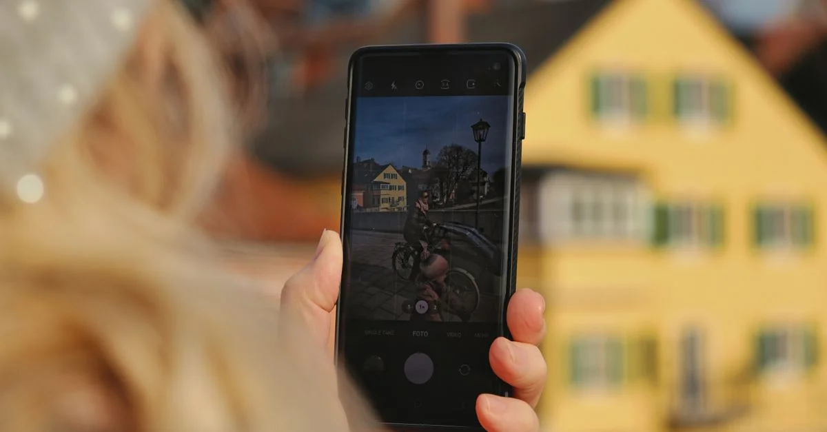 Gros plan sur une personne utilisant un smartphone pour capturer un cadre urbain pittoresque par une journée ensoleillée.