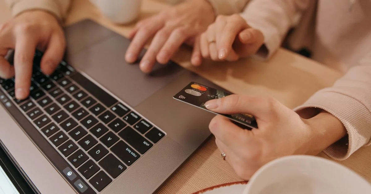 Gros plan de mains utilisant un ordinateur portable et une carte de crédit pour un paiement ou une transaction d'achat en ligne.