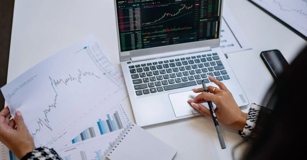 Un aperçu détaillé de l'analyse commerciale avec un ordinateur portable affichant des graphiques et des tableaux financiers sur une table.